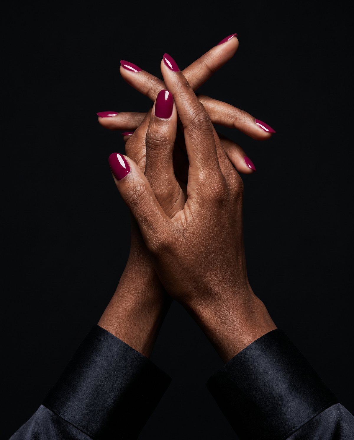 Close editorial de mãos cruzadas com unhas em magenta